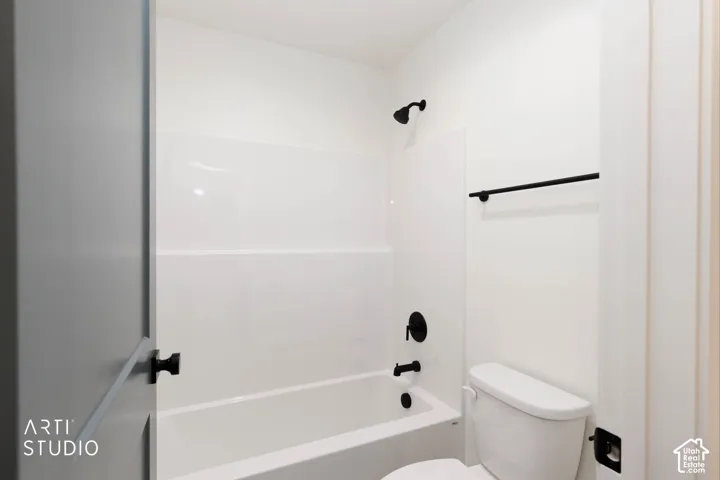 White bathtub with matte black fixtures, white toilet, and a black towel bar