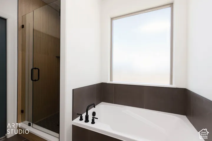 Built-in soaking tub with matte black fixtures, set against a tiled surround