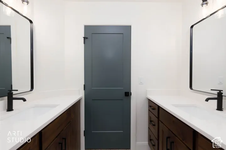 Dual vanities featuring built-in wood-finish cabinetry, integrated white sinks, and matte black fixtures
