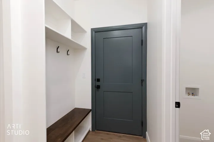 Built-in bench with wood-finish top, white shelving, and black coat hooks