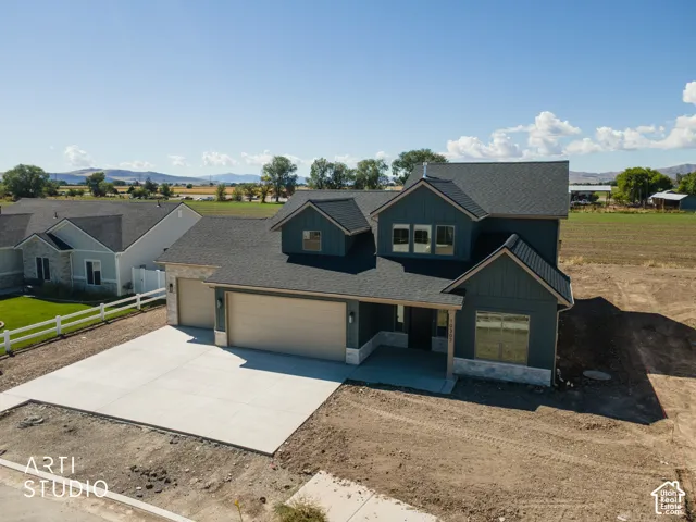 Two-story exterior with dark siding and stone accents, concrete driveway, and attached two-car garage