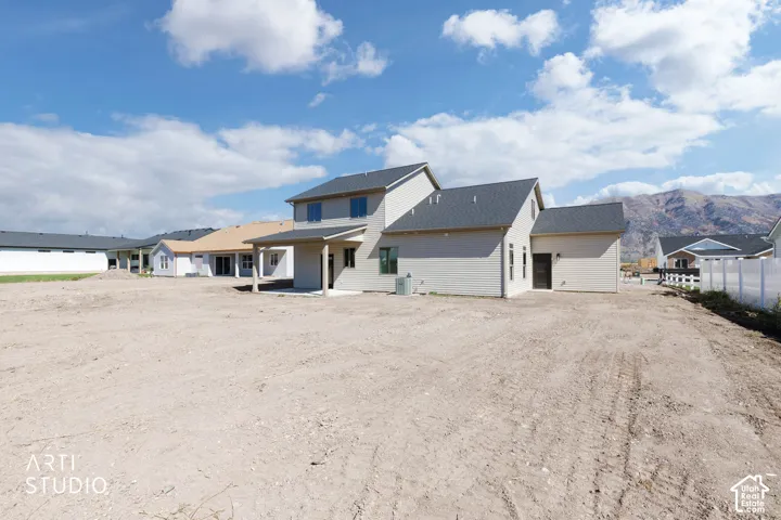 Two-story residence with light-toned siding, dark shingled roofing, and a covered back patio