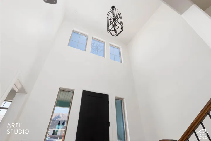 Double-height entry with a contemporary open-cage chandelier, sidelight windows, and a dark-paneled door