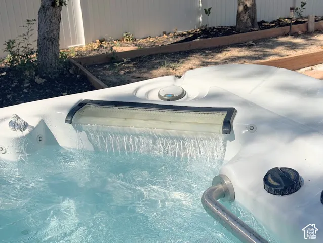 White spa with waterfall feature, stainless steel grab bar, and integrated control knobs