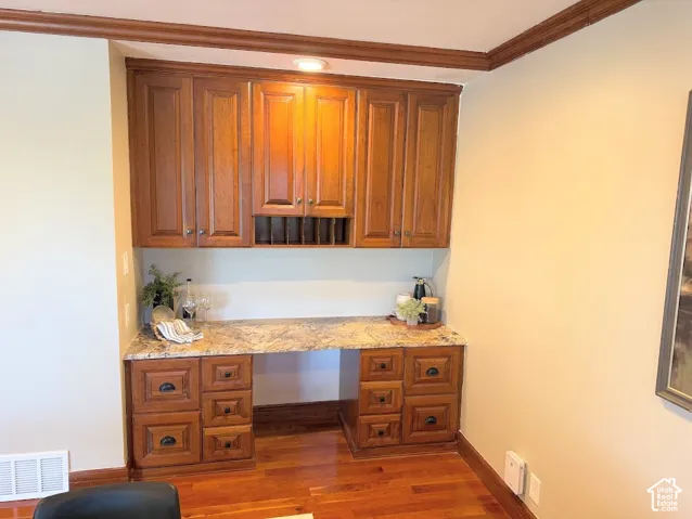 Built-in desk with a granite-style countertop, wood cabinetry, and recessed lighting