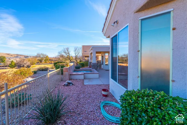 Outdoor spa with adjacent patio area, stucco exterior, and a metal fence
