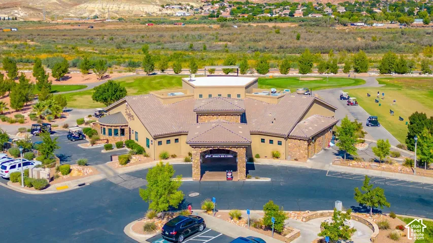 Golf Clubhouse & Restaurant featuring a multi-level building with a tile roof, a paved parking area, and surrounding green spaces