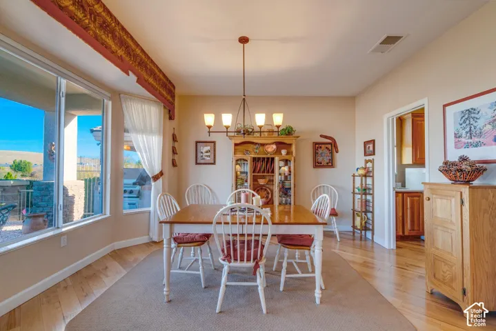 Recessed lighting and a multi-light chandelier illuminate this room with wood-finish flooring