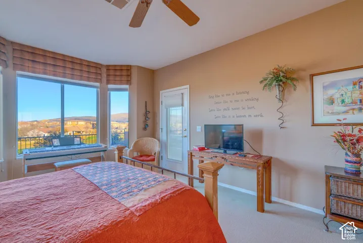 Recessed windows with blinds, ceiling fan, carpeted flooring, and a white door leading to an exterior space
