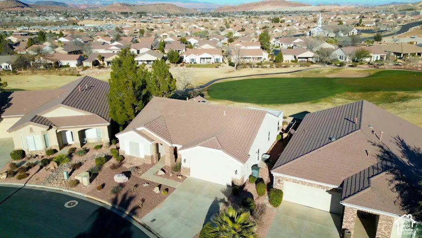 Residential property featuring a paved driveway, attached garage, and arid landscaping with mature trees