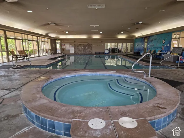 Indoor aquatic center featuring a spa, lap pool, and extensive window-lined walls
