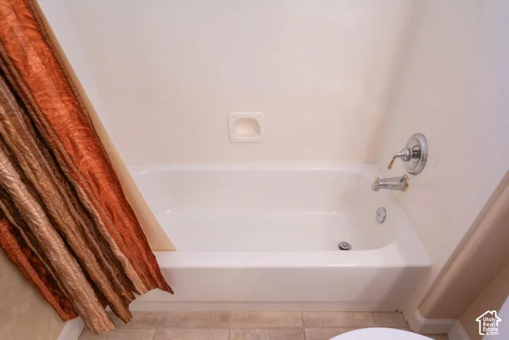 White bathtub with chrome and brass fixtures and a built-in soap dish