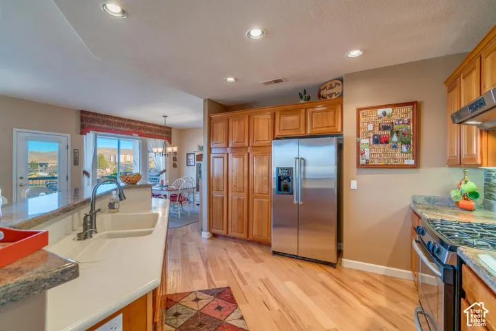 Stainless steel appliances, wood-finish flooring, light wood cabinetry, white double basin sink, and recessed lighting