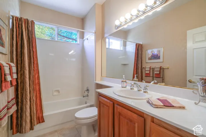 Built-in bathtub with a shower and white surround, wood-finish vanity with an integrated sink, polished chrome faucet, and a large wall-mounted mirror