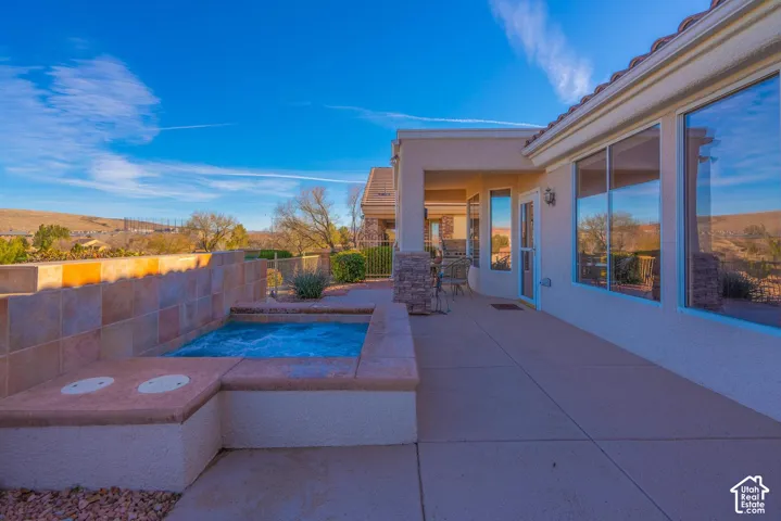 Patio area featuring an integrated spa, tiled privacy wall, and expansive window lines