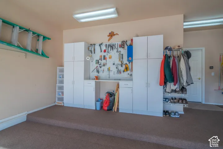 Built-in cabinetry with white finishes, pegboard storage, and integrated workbench