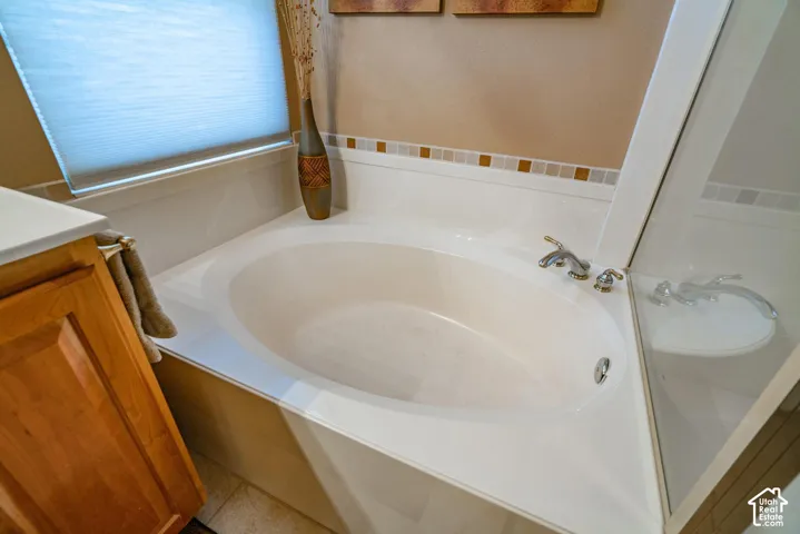 Built-in corner soaking tub with chrome fixtures, tiled backsplash accent, and a glass shower enclosure