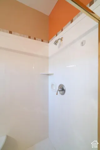 Shower enclosure with white paneling and a built-in corner shelf