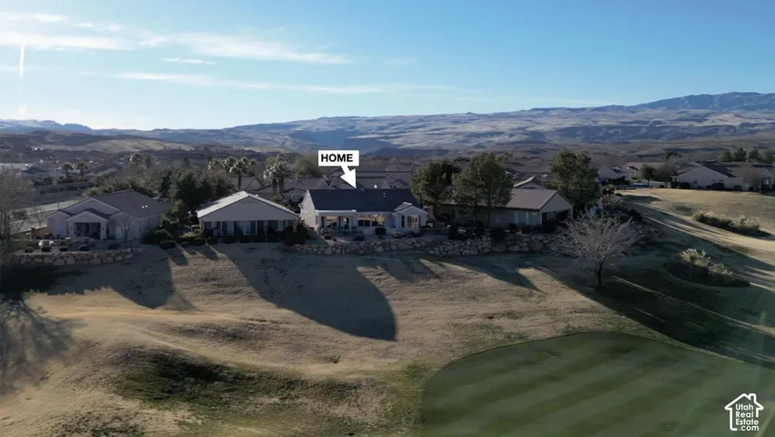 Single-story home featuring a covered patio, a stone retaining wall, and mature landscaping