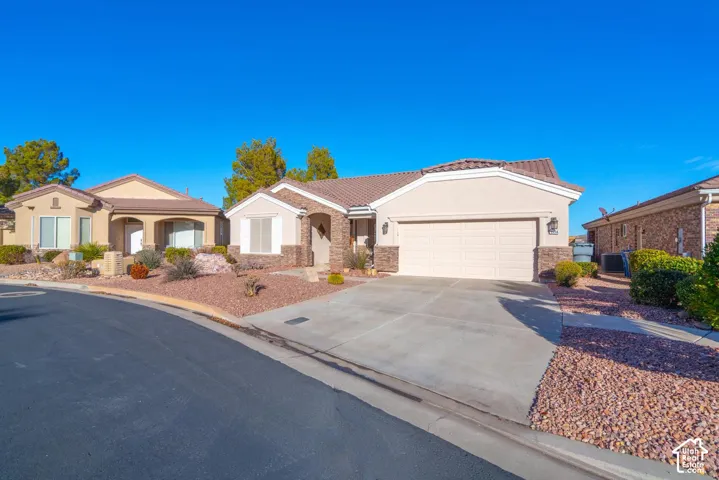 Single-story residence featuring a stucco exterior, stone accents, tile roof, and an attached two-car garage