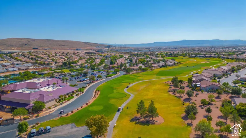 Sprawling golf course with manicured greens, surrounded by residential properties and distant mountain ranges