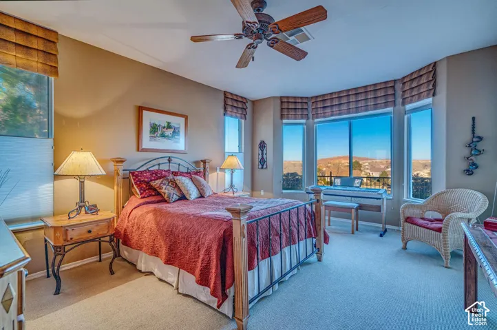 Bay window with exterior scenery, ceiling fan with light fixture, wall-to-wall carpeting, and neutral wall tones