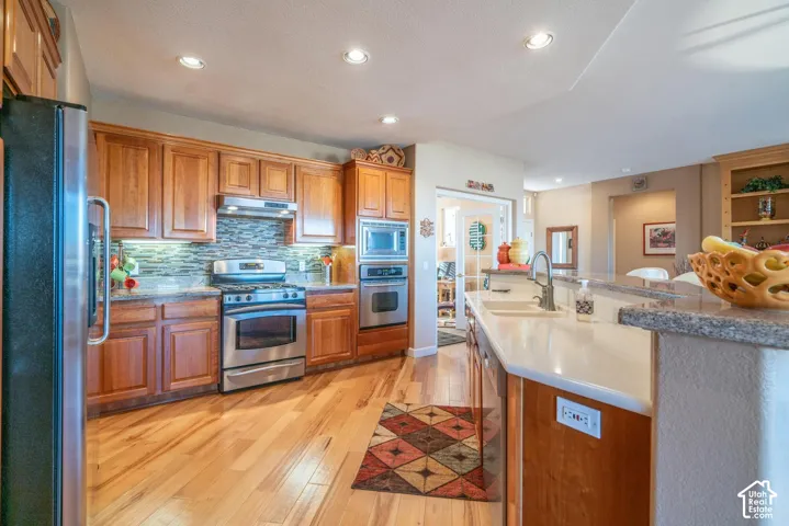 Kitchen featuring hickory flooring, stainless steel appliances, cherrywood cabinetry, recessed lighting, and a kitchen island with an undermount sink