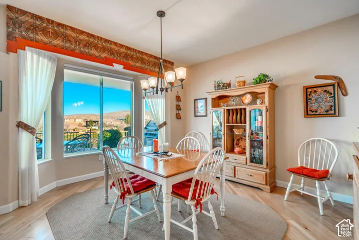 Expansive bay windows, light wood-finish flooring, neutral wall tones, and a built-in chandelier