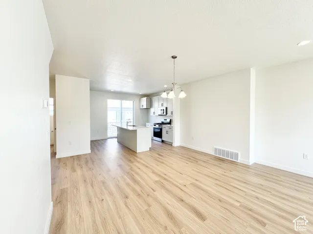 Open concept living space with wood-finish flooring, white walls, and recessed lighting