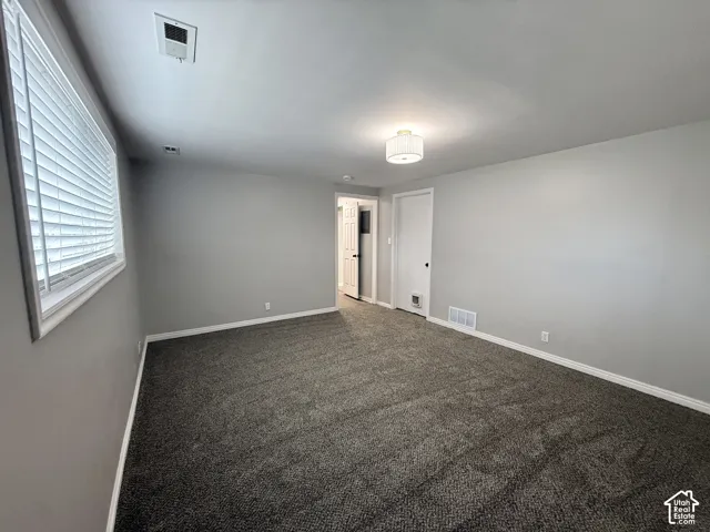Wall-to-wall carpeting with light gray walls, a window with horizontal blinds.