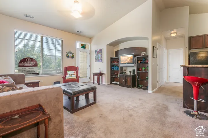 Archway entry, built-in entertainment center, ceiling fan, carpeted flooring, and a large window