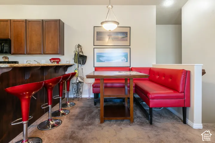 Kitchen area featuring wood-finish cabinetry, built-in microwave, and a breakfast bar with stone-look countertop