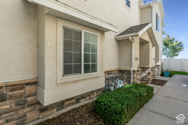 Stucco exterior with stone veneer accents, covered entry, and a prominent front window