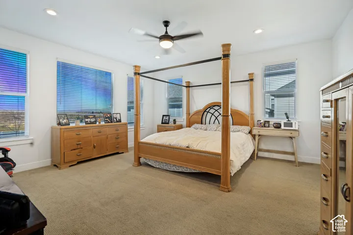 Recessed lighting, ceiling fan with integrated light, multiple windows with blinds, and neutral carpeting