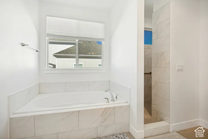 Deep soaking tub with tile surround, adjacent shower with full-height tile, and brushed nickel fixtures