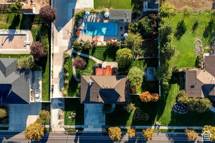 Property with an in-ground swimming pool, expansive grassy areas, and mature landscaping