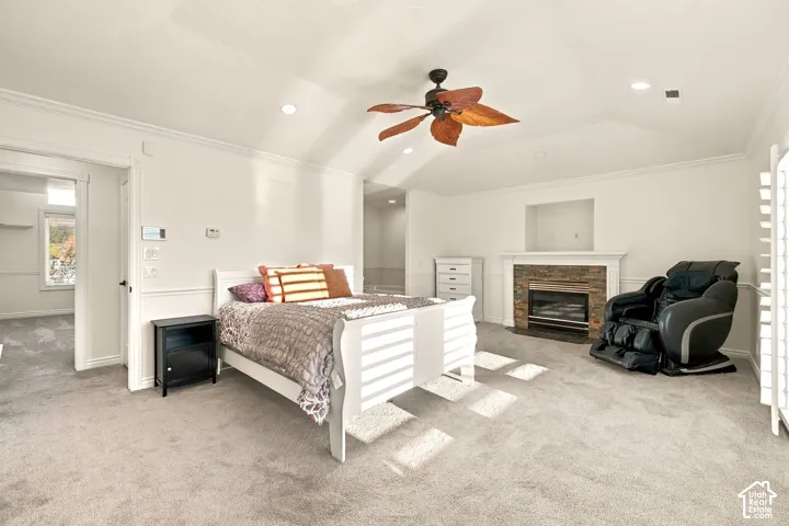 Vaulted ceiling with a ceiling fan, carpeted flooring, fireplace with a stone surround and white mantel, recessed lighting, and white plantation shutters