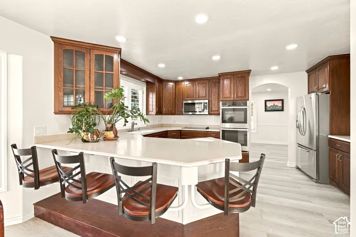 U-shaped kitchen with wood-finish cabinetry, light-toned countertops, and recessed lighting