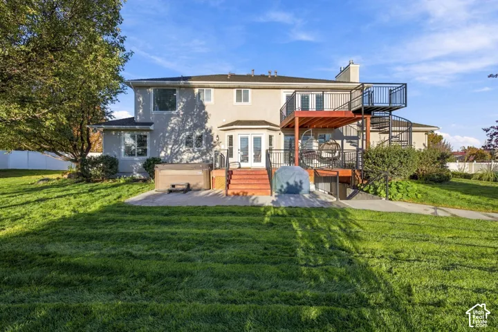 Expansive lawn with a two-story deck, spiral staircase, and ground-level patio