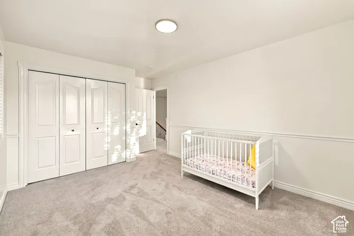 Expansive room featuring light gray carpeting, paneled walls, and white bi-fold closet doors