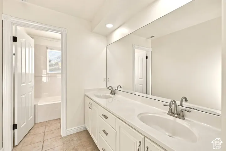 Dual vanity with white cabinetry, solid surface countertop, and brushed nickel fixtures