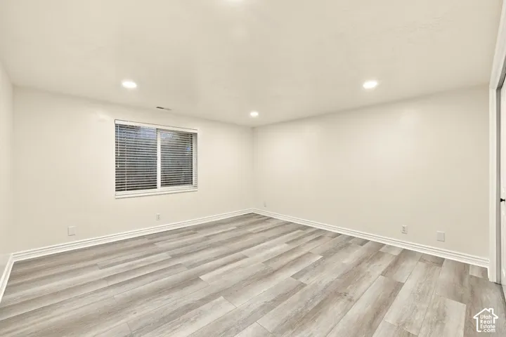 Wood-finish flooring, recessed lighting, and a white trim window with blinds