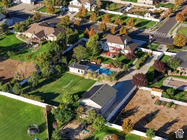 Expansive lot featuring a swimming pool, detached accessory building, mature landscaping, paved driveway, and established garden beds