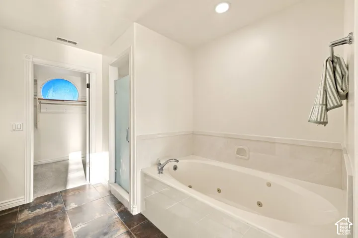 Spa-style bathtub with jets, tile surround, and a glass-enclosed shower