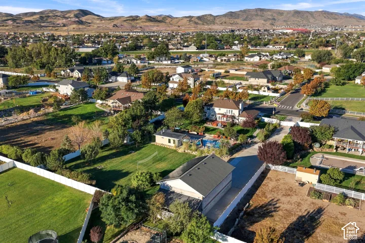 Expansive property featuring a large detached garage, paved driveway, white fencing, and a swimming pool