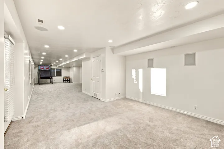 Spacious room featuring recessed lighting, light gray carpeting, white walls, and white trim