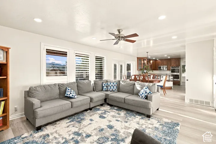 Recessed lighting, ceiling fan, wood-finish flooring, white plantation shutters, and a kitchen with wood cabinetry