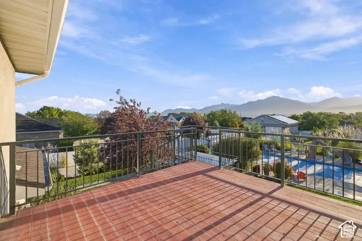 Expansive outdoor deck with a red-toned surface, black metal railings, and a mountain backdrop