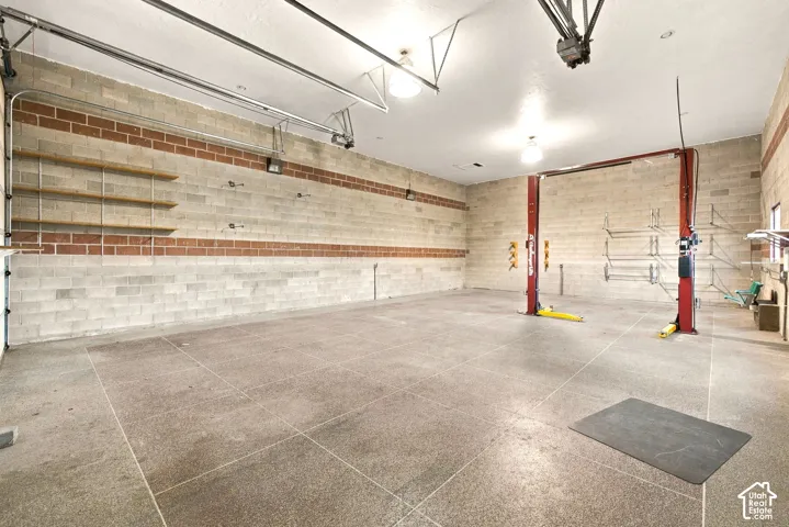 Spacious garage with concrete block walls, overhead lighting, and built-in shelving
