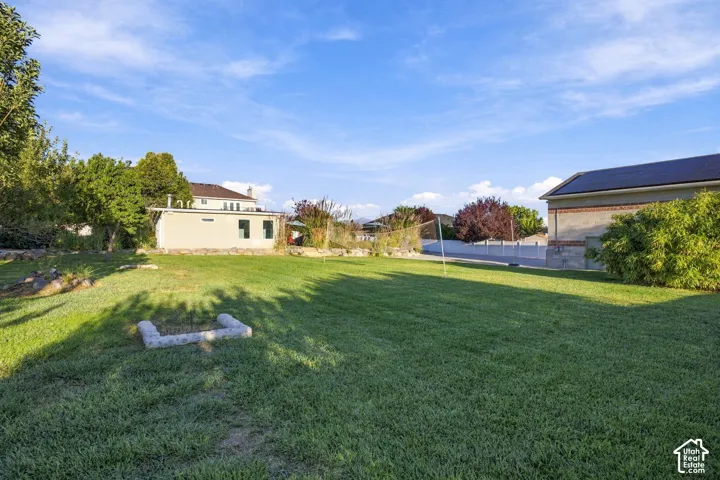 Expansive grass lawn with a concrete paver outline and a stucco-finish accessory building
